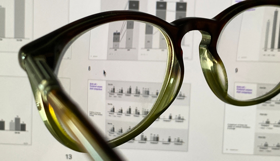 A pair of glasses with a data filled spreadsheet in the background